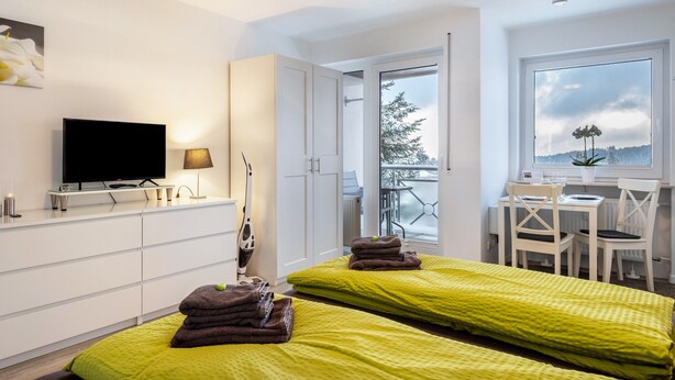 Une chambre d’hôtel moderne avec deux lits, une télévision, un bureau avec des chaises et une vue sur l’extérieur.