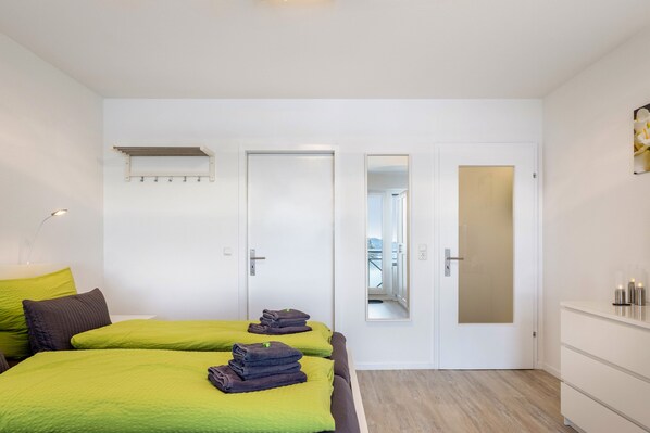 Un dormitorio con dos camas, un espejo, un armario y una puerta que da a un balcón.