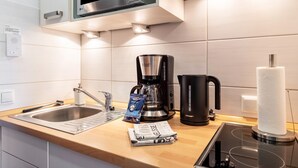 A modern kitchen with a stainless steel sink, a coffee maker, a kettle, and a paper towel holder. - Studio 'Schwarzwaldblick F with Pool App 3' with Balcony and Wi-Fi (Schönwald im Schwarzwald)