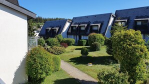 A row of residential buildings with sloped roofs, a well-maintained lawn, and a clear sky. - Studio 'Schwarzwaldblick F with Pool App 3' with Balcony and Wi-Fi (Schönwald im Schwarzwald)
