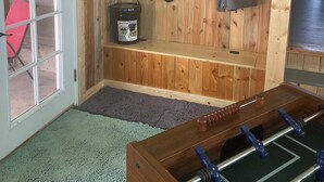 A cozy room with a wooden bench, a foosball table, and a red chair.