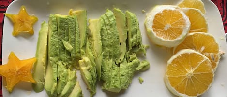 A plate with avocado slices and orange slices on a tablecloth with a geometric pattern.