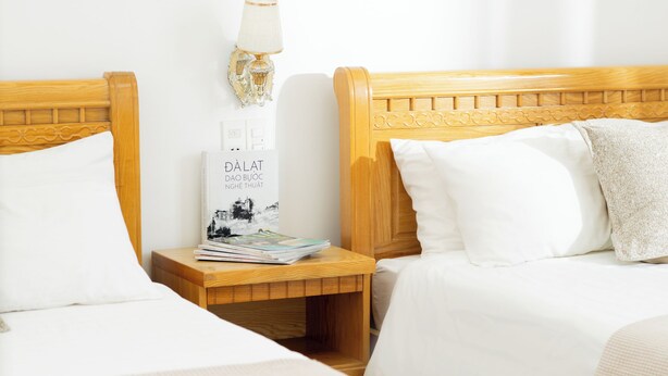 A hotel room with two beds, a nightstand with a lamp, and a framed picture on the wall. - AM MEMORY CENTRE HOTEL (Xuan Huong - Da Lat)