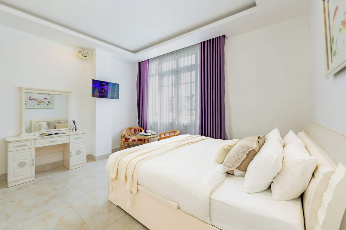 Un dormitorio con cama, escritorio, silla y televisión.
