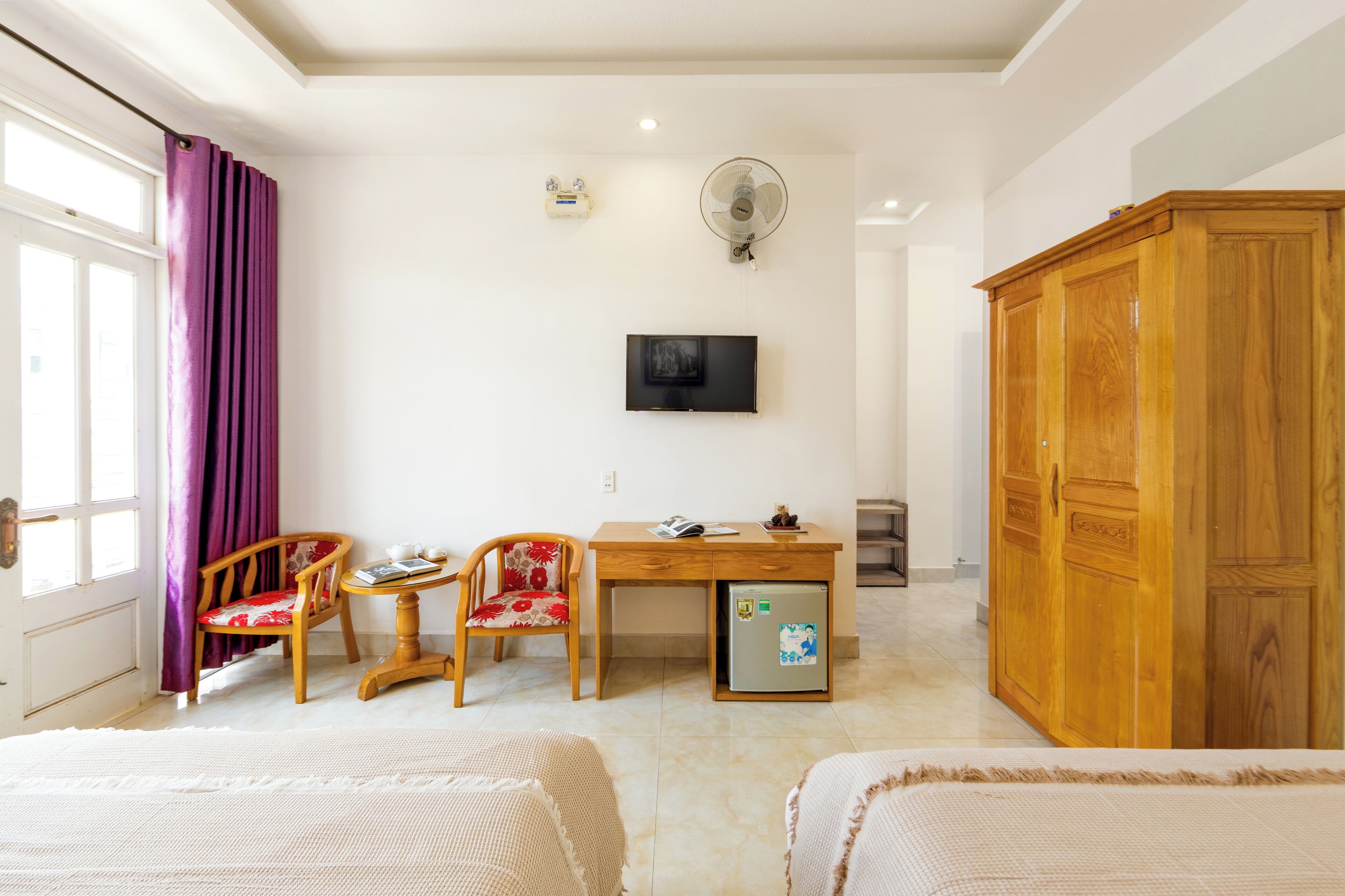 Een hotelkamer met een bed, een bureau met computer, een stoel, een kledingkast en een televisie aan de muur.