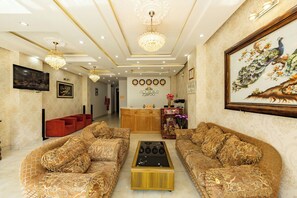 Eine luxuriöse Lobby mit aufwendigen Sofas, einem zentralen Couchtisch und einer dekorativen Decke.