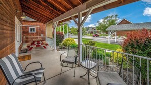 A covered porch with a view of a street, a picnic table, and two chairs. - Pet Friendly Dover Bay Getaway (Dover)