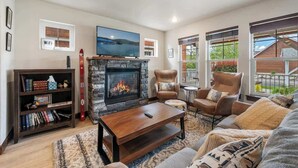 A living room with a stone fireplace, a flat-screen TV, a bookshelf, and a comfortable seating area with a view of the outdoors. - Pet Friendly Dover Bay Getaway (Dover)