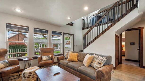 A spacious living room with a brown leather sofa, two armchairs, a coffee table, and a staircase leading to an upper level. - Pet Friendly Dover Bay Getaway (Dover)