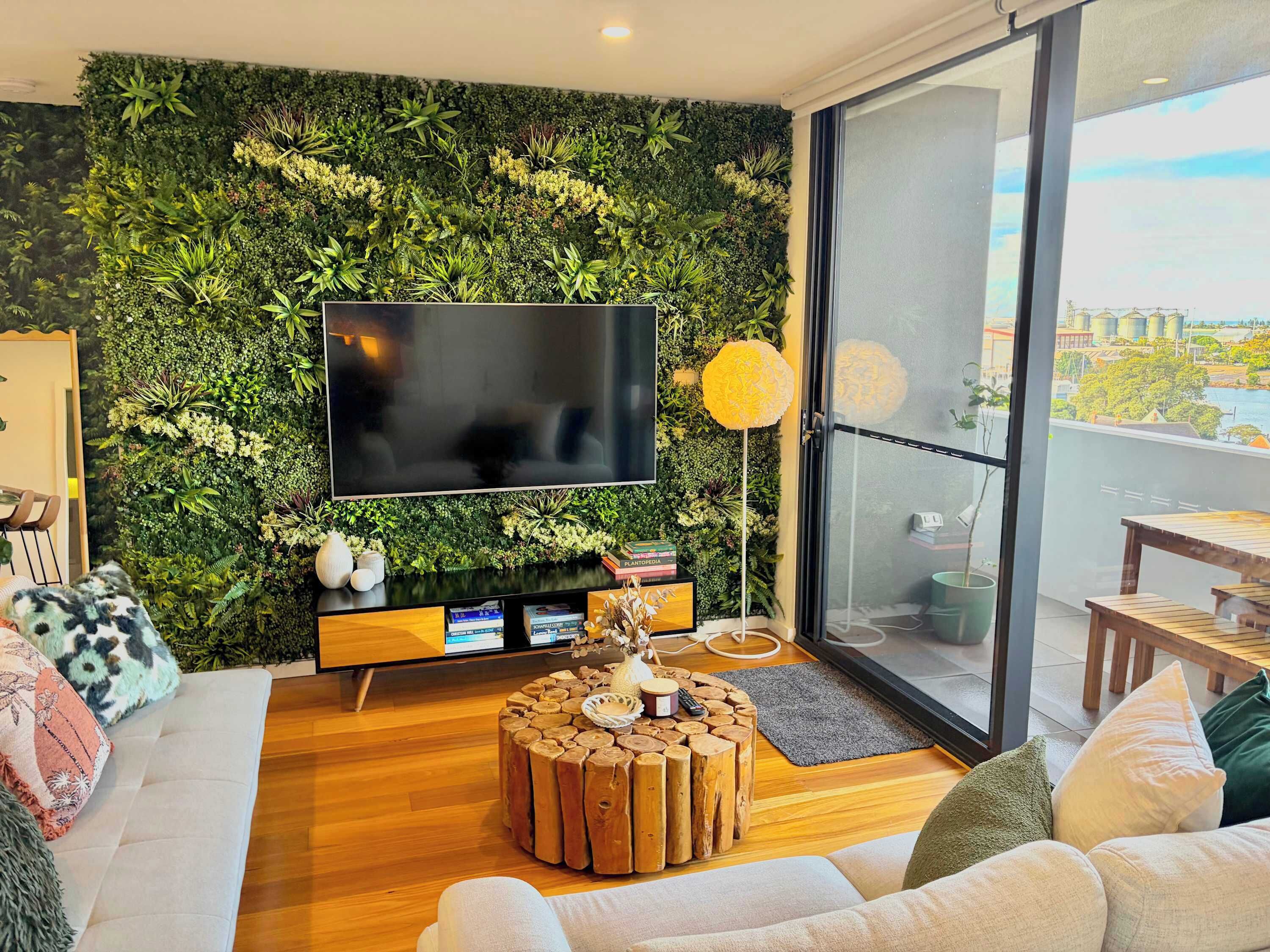 A modern living room with a green wall, a flat-screen TV, a wooden coffee table, and a sofa.