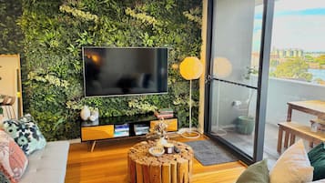 A modern living room with a green wall, a flat-screen TV, a wooden coffee table, and a sofa.