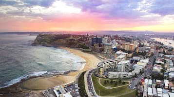 A coastal cityscape with a beach, buildings, and a road.