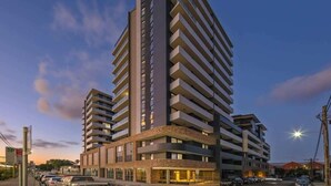 Un hôtel de grande hauteur doté de nombreux balcons, d’une entrée principale et d’un espace de stationnement.