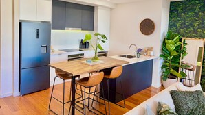 Une cuisine moderne avec un îlot central, des tabourets de bar, un évier et une horloge au mur.