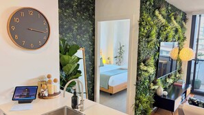 Une chambre d’hôtel moderne dotée d’un coin cuisine, d’un grand miroir et d’un mur végétal.
