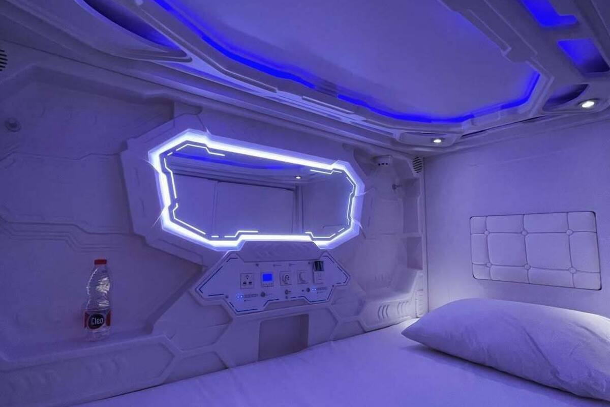 A futuristic room with a bed, a control panel, and a bottle of water.