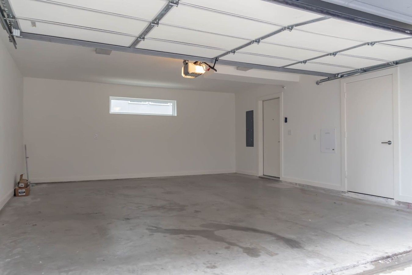 A spacious garage with a concrete floor, a single window, and a door.