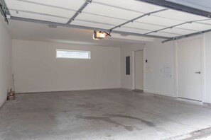 A spacious garage with a concrete floor, a single window, and a door. - Dallas 2BR Retreat | Rooftop Patio & Stunning Downtown Skyline (Dallas)