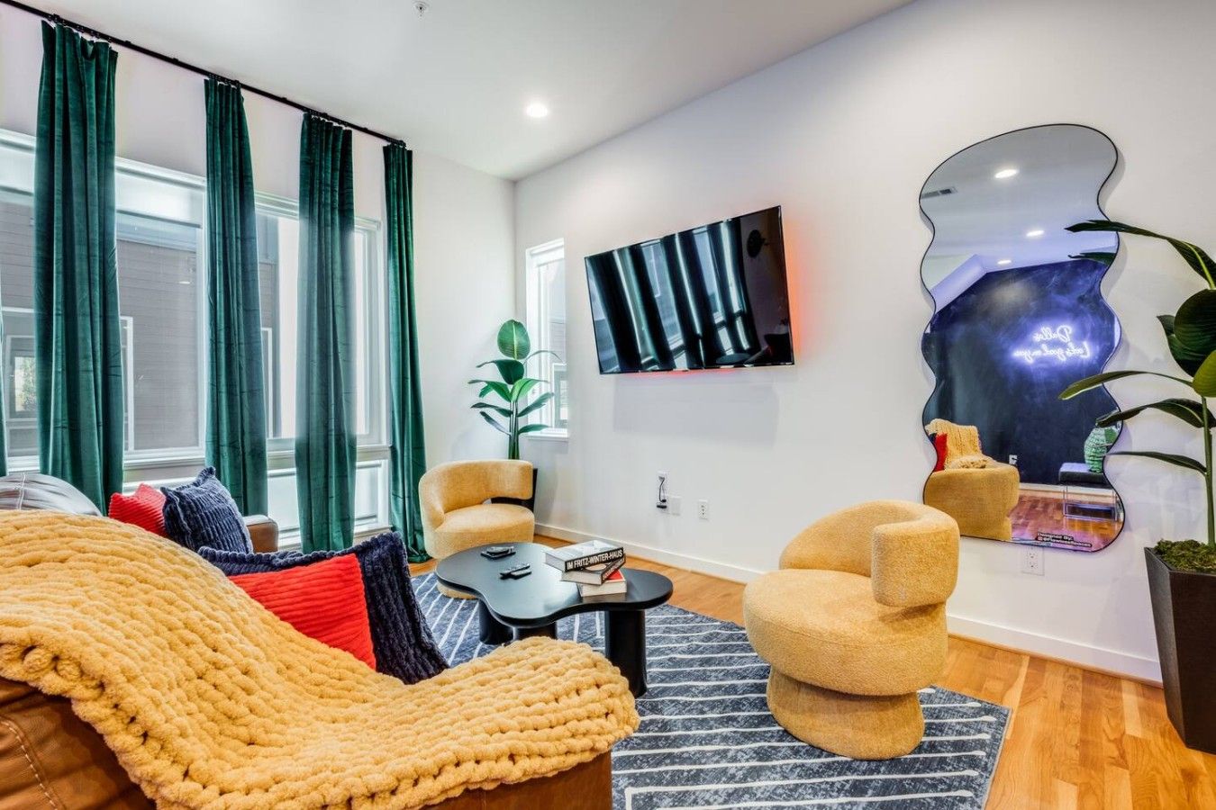 A modern living room with a sofa, armchairs, a coffee table, and a flat-screen TV mounted on the wall.