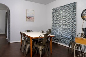 A dining area with a table and chairs, a clock, and a patterned curtain. - Corinth 3BR | BBQ Grill + Backyard & Playground (Corinth)