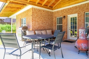 An outdoor patio with a brick wall, a round table, and chairs.