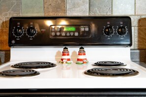 A GE electric stove with four burners and a digital clock displaying 3:06. - Lighthouse-Themed Lake House Escape (Nocona)