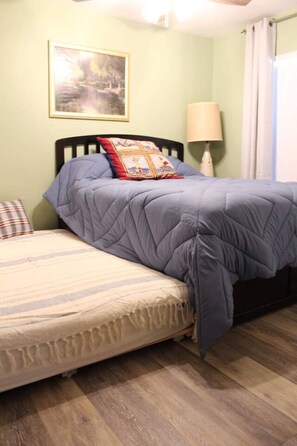 Een slaapkamer met twee bedden, een lamp en een schilderij aan de muur.