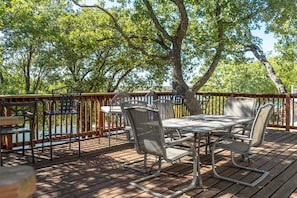 An outdoor deck with a table and chairs, surrounded by trees.