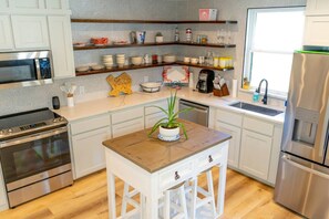 A modern kitchen with stainless steel appliances, wooden countertops, and a central island with a potted plant.