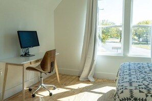 A bedroom with a bed, a desk with a computer, a chair, and a window with curtains. - 3BR Saint Jo Getaway | BBQ, Fire Pit + Comfort (Saint Jo)