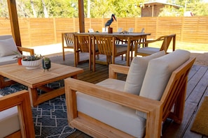 An outdoor patio with wooden furniture, including a sofa and tables, and a wooden deck. - 3BR Saint Jo Getaway | BBQ, Fire Pit + Comfort (Saint Jo)