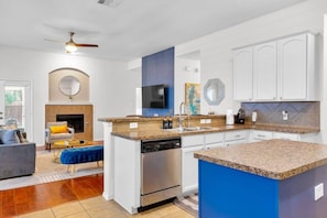 A modern kitchen with a central island, white cabinetry, and a blue accent wall. - Pet-Friendly Retreat | Yard, Grill + Workspace (McKinney)