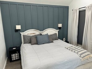 A bedroom with a bed, nightstands, and a window with curtains.