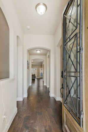 A hallway with a wooden floor, white walls, and a large glass door with metal framing. - Stylish 3BR Near Lake & Downtown w/ Patio & WiFi (Fort Worth)
