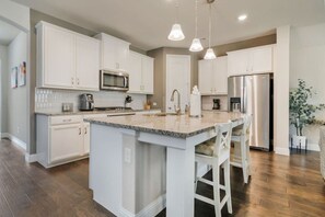 A modern kitchen with white cabinetry, a granite countertop, stainless steel appliances, and pendant lighting. - Stylish 3BR Near Lake & Downtown w/ Patio & WiFi (Fort Worth)