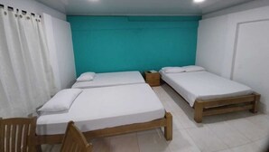 A room with three single beds, a wooden chair, and a small table.