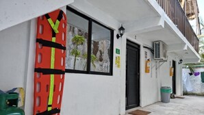 A building exterior with a fire escape ladder, a door, an air conditioning unit, and a trash bin.