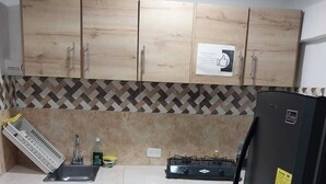 A kitchen with wooden cabinets, a gas stove, a sink, and a refrigerator.