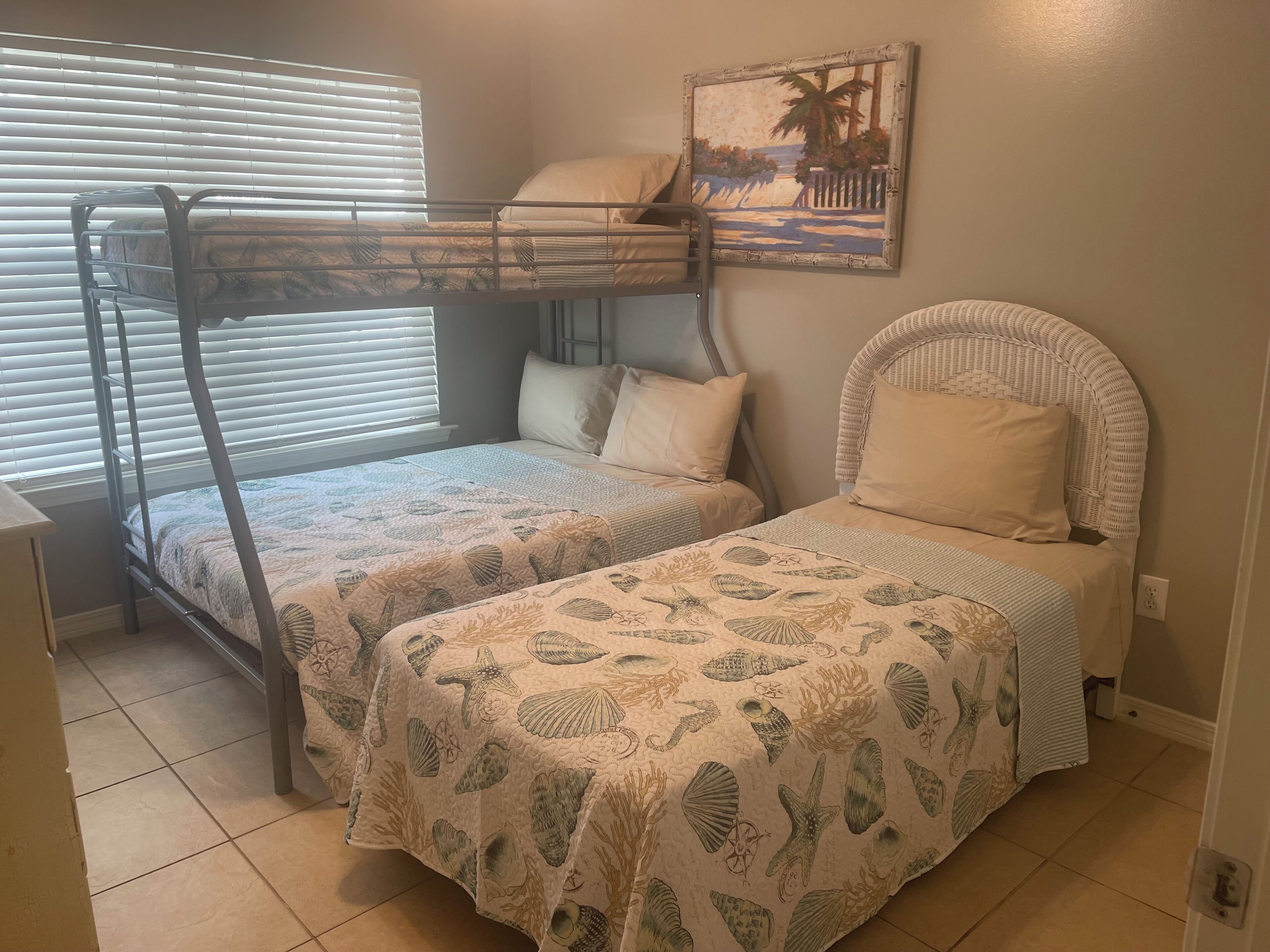 Une chambre avec des lits superposés et un lit simple, tous deux dotés de draps à motifs.