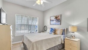 A bedroom with a bed, bedside table, lamp, and a ceiling fan. - Charming 3 BR, 2 BA cottage with pool, perfectly nestled in Orange Beach. (Orange Beach)