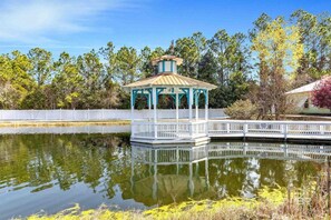 A gazebo with a white railing and a roof, surrounded by a body of water and trees.