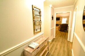 A hallway with a wooden bench, a wall-mounted light fixture, and a door leading to a living area.