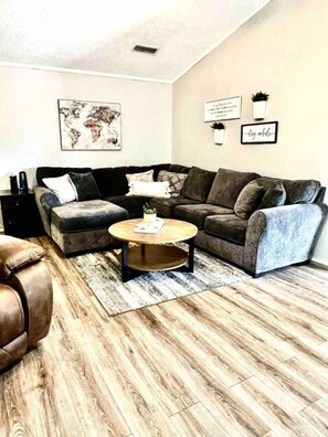 A living room with a sectional sofa, a coffee table, and a world map on the wall.