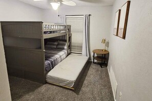 A compact room with bunk beds, a small round table, and a window with curtains.