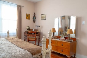 Ein Schlafzimmer mit einem Bett, einem Holzschrank, einem Schreibtisch und einem großen Spiegel.