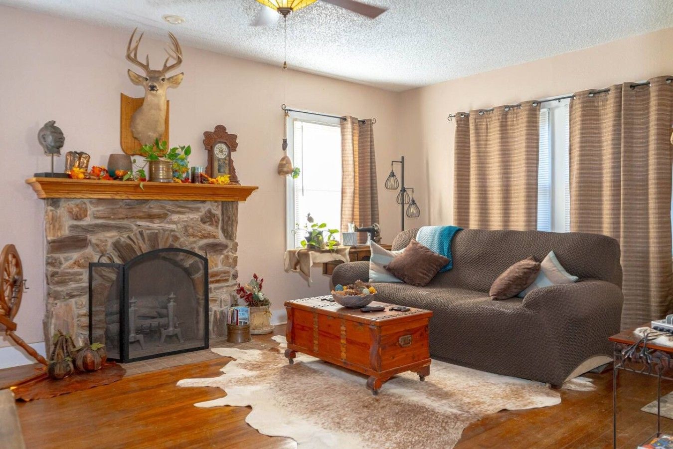 Un salon chaleureux avec une cheminée en pierre, un canapé et un tapis en peau de vache.