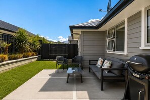 A patio area with a table, chairs, a sofa, and a barbecue grill.