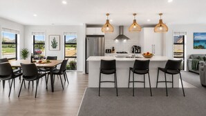 A modern kitchen with a central island, black bar stools, and pendant lighting. - Mountain View - 2 Bedroom House (Queenstown)