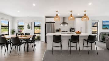 A modern kitchen with a central island, black chairs, and pendant lighting.
