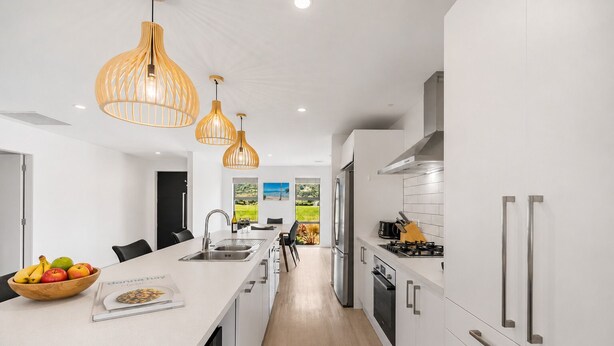 A modern kitchen with white cabinetry, a central island, and pendant lighting. - Mountain View - 2 Bedroom House (Queenstown)